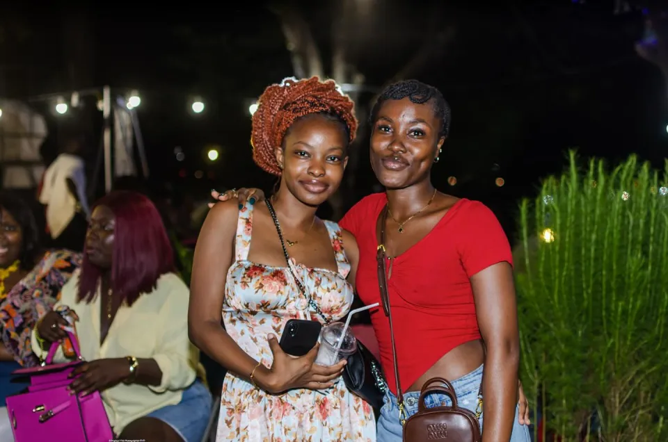 Two friends smiling beneath strings of lights