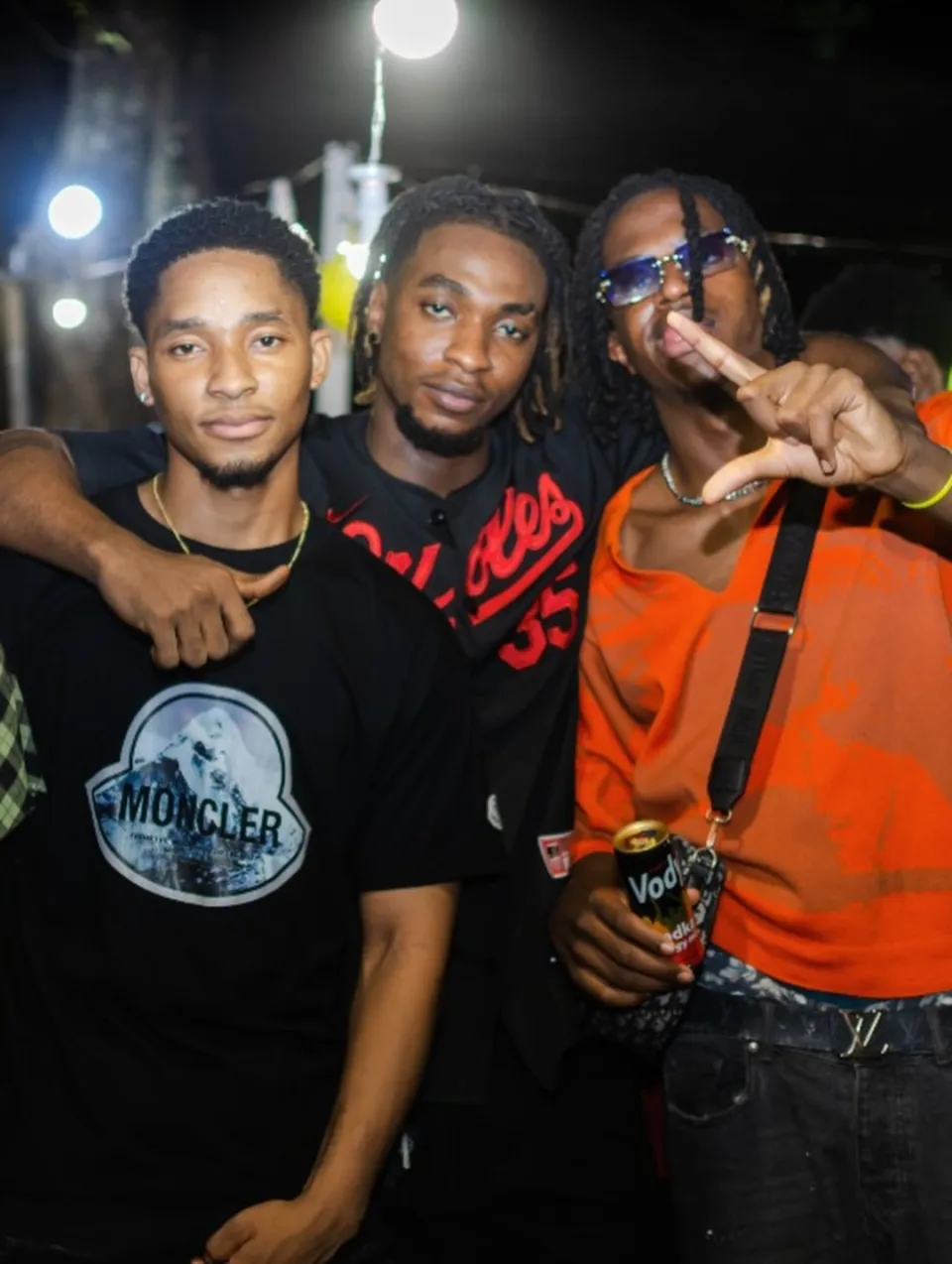 Three friends posing together outdoors at night