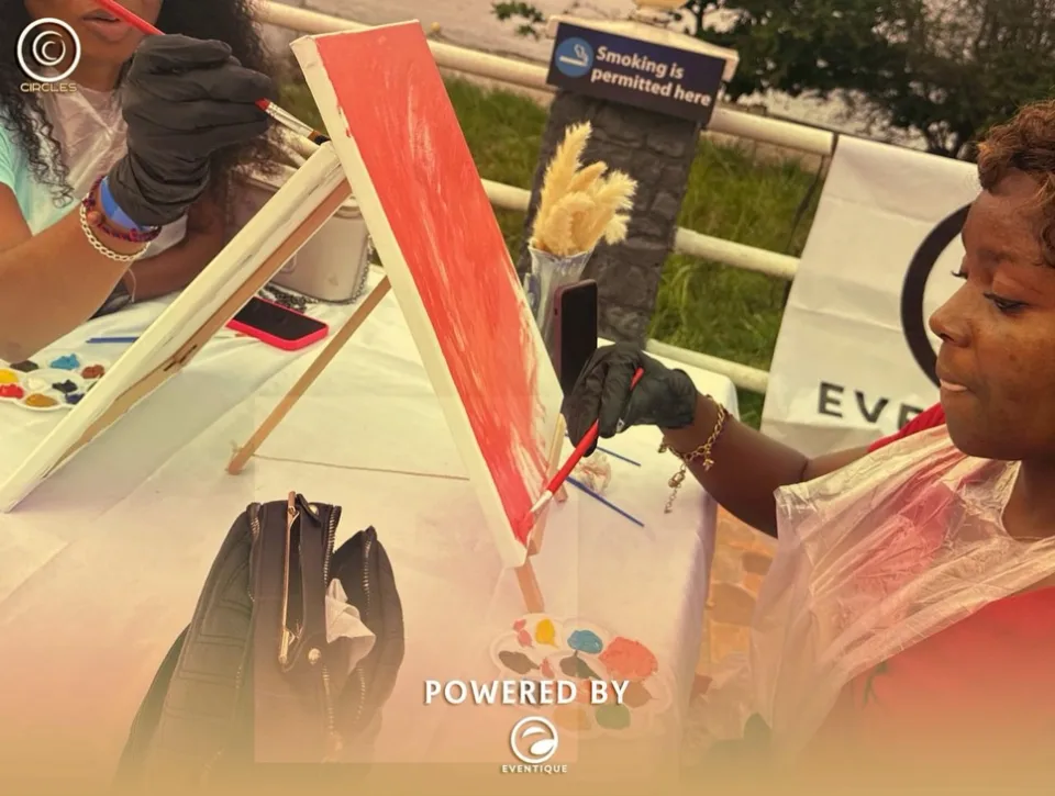 A guest working on a bright orange canvas at the sip-and-paint corner